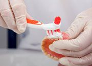 Eine Vollprothese wird mit spezieller Paste gereinigt